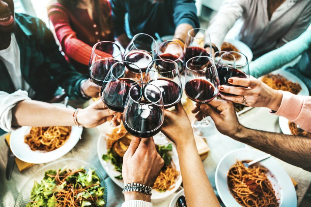 Happy friends toasting red wine glasses at diner party